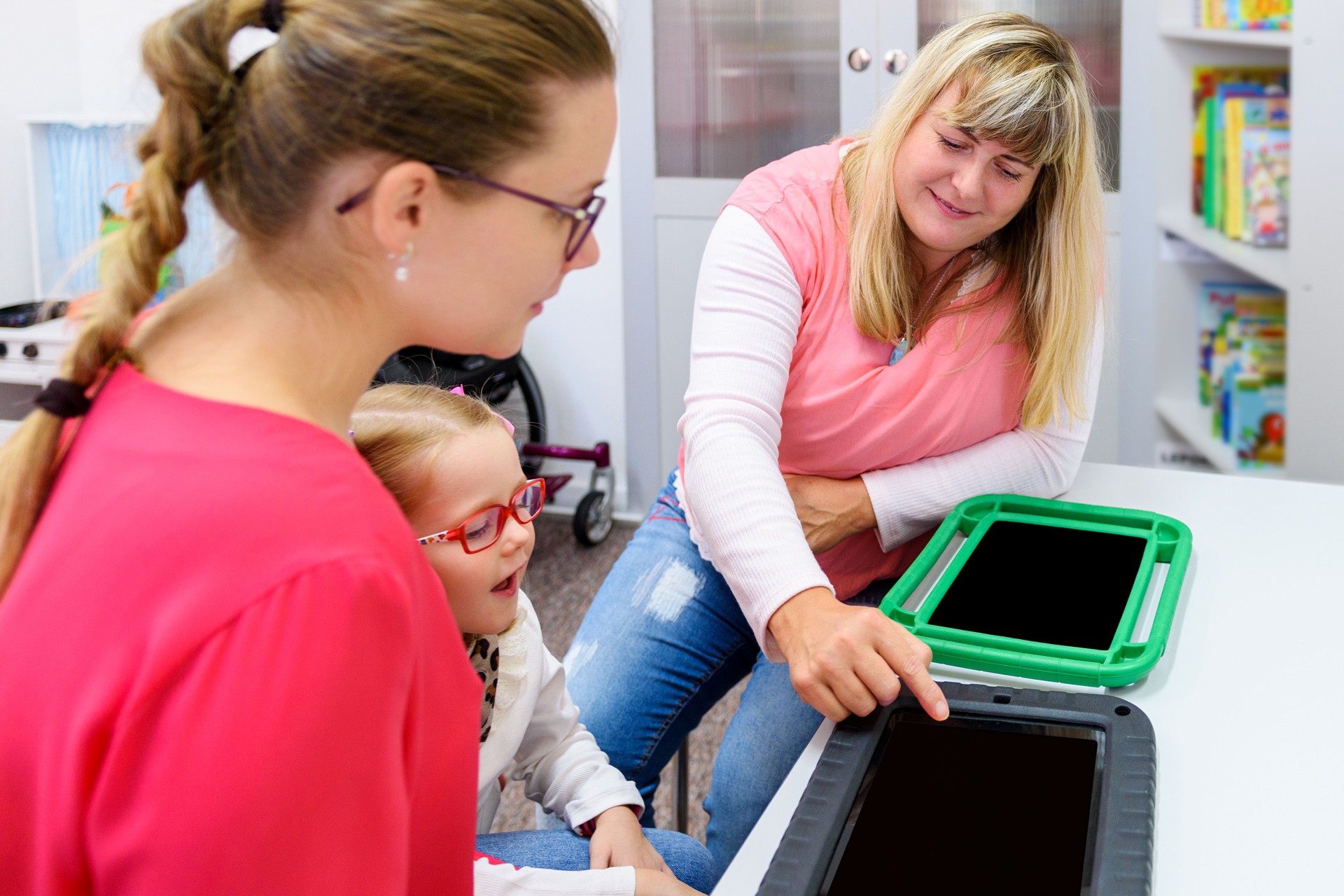 Non-verbal girl living with cerebral palsy, learning to use digital tablet device to communicate. People who have difficulty developing language or using speech use speech-generating devices.